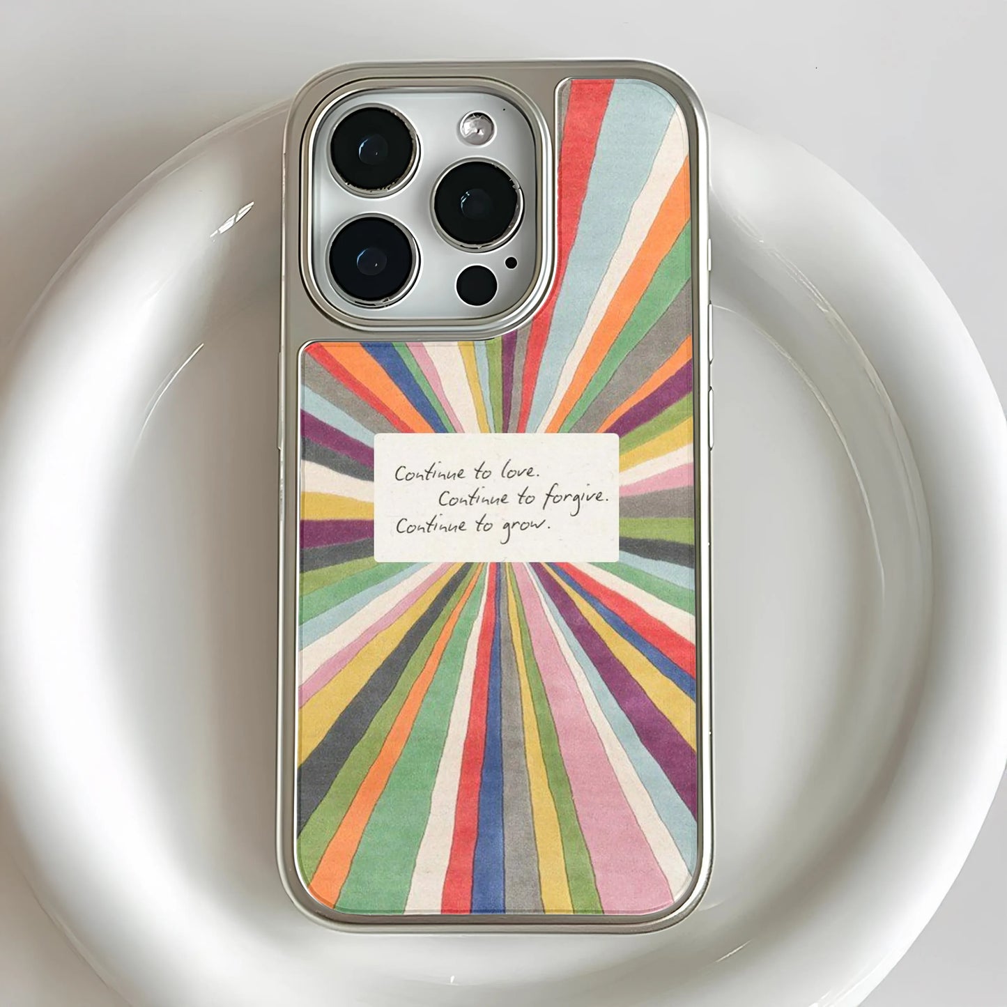 Colorful sunburst illustration with an inspirational handwritten note in the center reading: "Continue to love. Continue to forgive. Continue to grow."